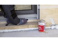 Eine Dose Grundierung Weich-PVC 1K-Flüssigkunststoff neben dem Handwerker welcher es an einem Fenster nutzt