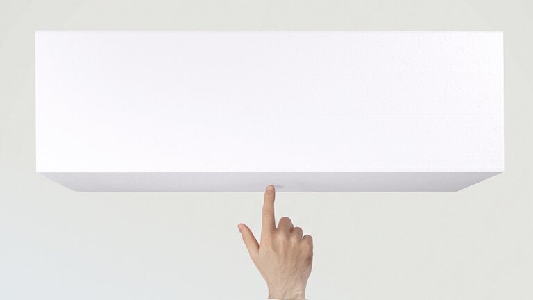 Extrem leichte weiße EPS-Dämmplatte auf einem Finger.