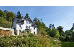 Das Gästehaus Tauhaus in Manetin Tschechien, auf einem begrünten Hügel mit Gartenanlage. | © Clocal Consulting