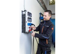 Elektriker steckt Industriestecker in Wandverteiler ein.