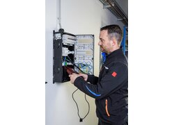 Elektriker prüft offenen Stromverteiler an der Wand.