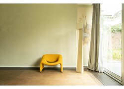 Gelber Designer-Sessel vor einer hellen, verputzten Wand.