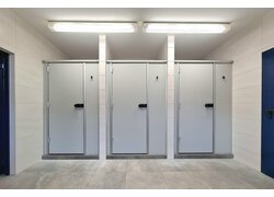 Helle graue Toilettenkabinen mit schwarzen Griffen.