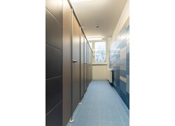 Reihe brauner Toilettenkabinen mit blauen Fliesen.