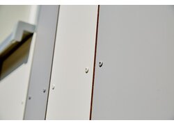 Nahaufnahme einer glatten, weißen Verkleidung mit sichtbaren Befestigungsschrauben für einen schlichten Look.
