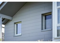 Schlichte graue Holzverkleidung mit klaren Linien an einem Haus, die für ein minimalistisches Erscheinungsbild sorgt.