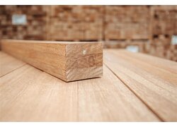 Hartholzpfosten auf Holzuntergrund mit rötlicher Maserung.