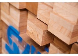 Gestapelte quadratische Holzblöcke mit feiner rötlicher Maserung.