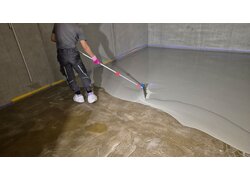 graue Epoxidharz-Beschichtung mit einem Rakel auf einem Betonboden.