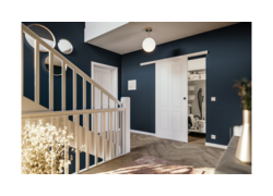 Eleganter Flur mit dunkelblauen Wänden, Holztreppe und weißer Schiebetür
