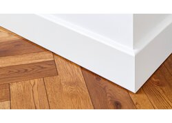  Weiße Sockelleiste an Wandecke über hellem Holzboden.