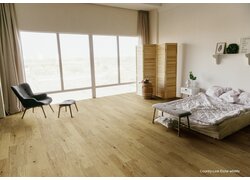 Helles Schlafzimmer mit Eichenparkett und großem Fenster.