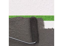 Farbrolle streicht Wand, grünes Malerband schützt.