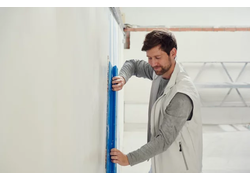 Mann glättet weiße Wand mit Werkzeug.