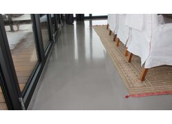 Ein feiner LAFINA Terrazzo der auf den ersten Blick kein Muster aufweist. Er ist in hellem Grau, glänzt und befindet sich in einem Esszimmer, welches an eine Terrasse angrenzt