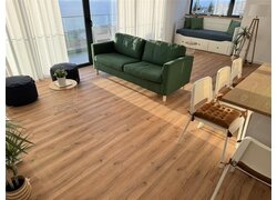 Helles Wohnzimmer mit Holzfußboden und grüner Couch.