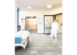 Verlegter Designboden "floors@work" in hellgrauer Fliesenoptik in einem Krankenhaus.