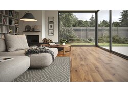 SKAVA Rigid Klick Vinyl - Home SKAVA Rigid Klick Vinyl Home, verlegt im Wohnzimmer mit Holzoptik. Links sieht man Teppich, Sofa, Bücherregal und Lampe mit Beistelltisch. Gerade und rechts sieht man aus bodentiefen Fenstern in den Garten und auf die Terrasse