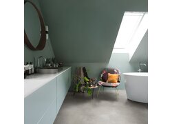 Modernes Badezimmer mit grünlichen Wänden, freistehender Badewanne und floralem Sessel.