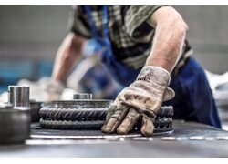 Mann mit Handschuh bei Montage industrieller Zahnräder.