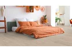 Schlafzimmer mit orangefarbenen Kissen und Pflanzen.