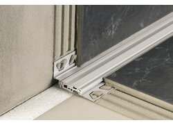 Ecke, in der Wand- und Bodenfliesen durch ein speziell geformtes Aluminiumprofil verbunden werden.