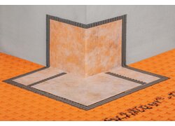 Abdichtungsecken aus Polyethylen-Folie mit beidseitig eingebundenem Vliesgewebe auf einer orangefarbenen Entkopplungsmatte der Firma Schlüter.