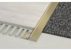  Nahaufnahme eines Bodenübergangsprofils aus Messing, das zwei unterschiedliche Bodenbeläge trennt.