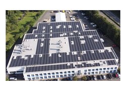 Ein großes Bürogebäude mit Flachdach und Solaranlage. Unter der Solaranlage sind VAEPLAN Solar Dachbahnen verlegt.