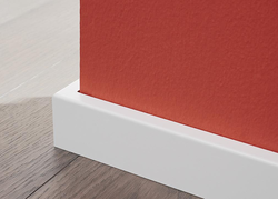 Weiß folierte Sockelleiste, die sauber an rot gestrichener Wand und Holzboden abschließt.