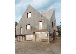 Graues Satteldachhaus mit Korkplattenfassade und Glasfront.