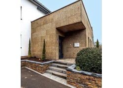 Eingangsbereich mit Korkfassade und Stufen.