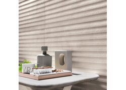 Helle Wandfliesen mit horizontaler, wellenartiger Reliefstruktur.
