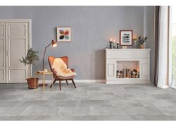Gemütliches Wohnzimmer mit Sessel, Stehlampe und Kaminattrappe.
