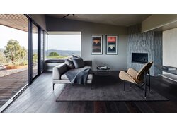 mafi Naturholzboden Eiche in einem Wohnzimmer mit Sofa, Sessel und Kamin. Alles äußerst modern und minimalistisch. Links eine Fensterfront/ Terrasse mit Blick in die Berge