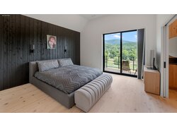 mafi Naturholzboden aus Nadelholz in einem Schlafzimmer. Mittig ein Doppelbett, schräg daneben eine Balkontür mit Sicht in die Berge