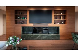 Dunkler mafi Naturholzboden Nuss vor einer modernen Fernsehwand aus Holz mit integriertem Kamin unter dem Fernseher mittig.
