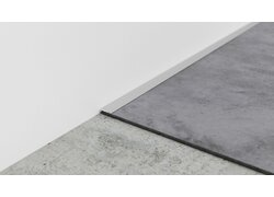 Metallkante trennt zwei Bodenbeläge an Wand