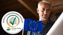 Mann insipiziert Bauplan. Davor ist das SHI-Schadstoffgeprüft-Siegel mit europäischer Flagge